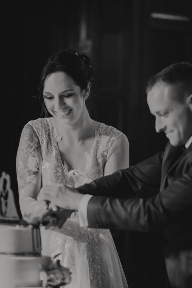 Braut und Bräutigam schneiden gemeinsam die Hochzeitstorte an.