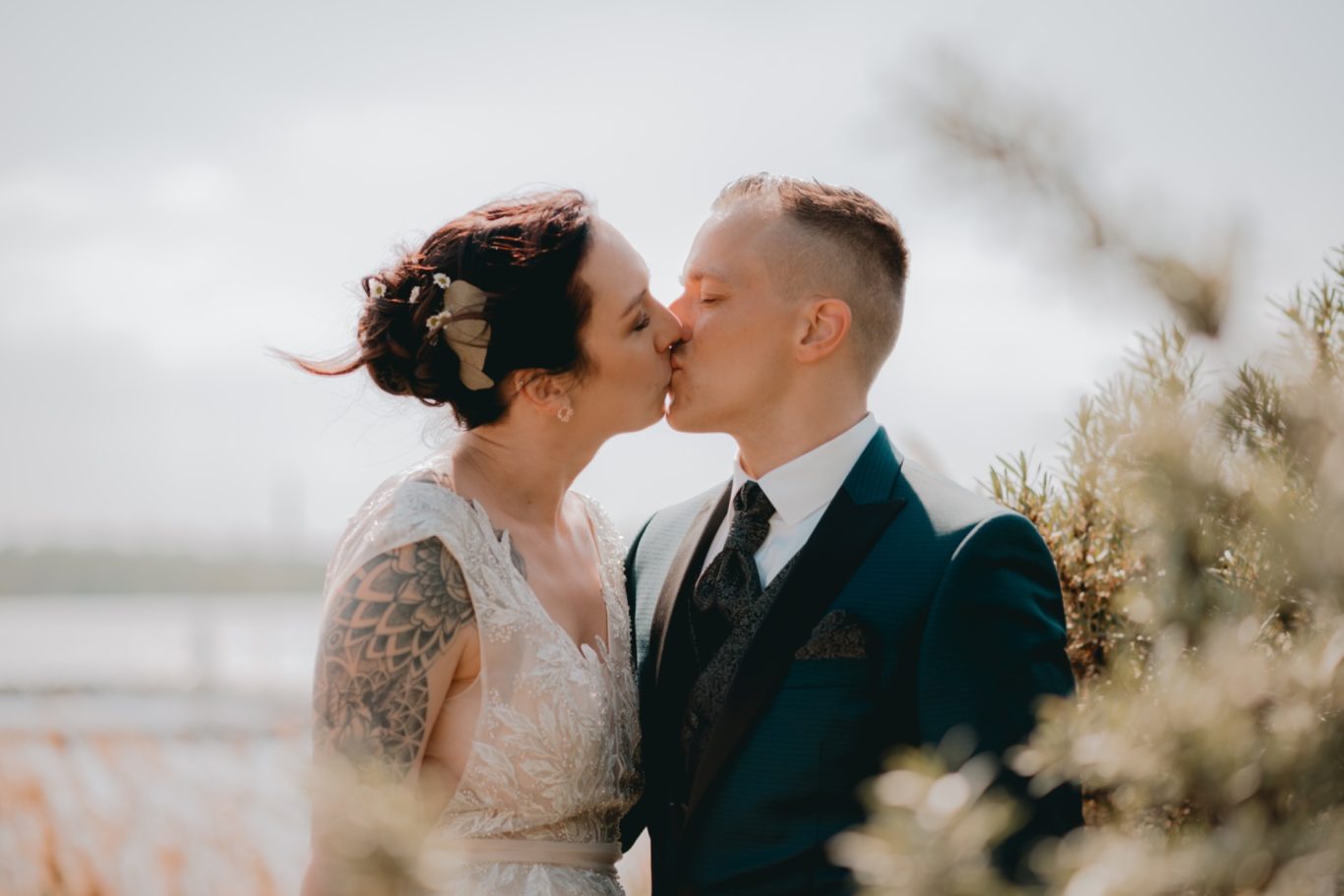 Braut und Bräutigam küssen sich romantisch vor einer malerischen Kulisse.