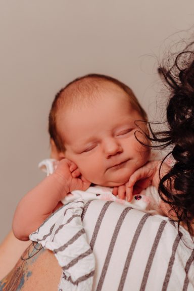 Ein schlafendes Baby in den Armen einer Person, mit sanften Gesichtszügen.