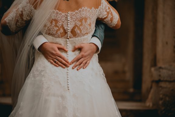 Hochzeitskleid mit handgemachtem Herzsymbol, Hände umschlingen taillierten Bereich.