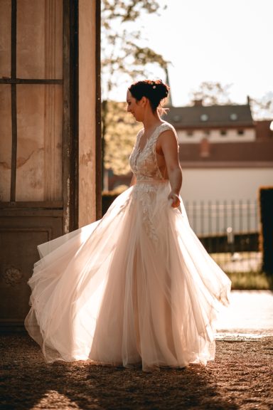 Eine Braut in einem eleganten, schwingenden Kleid beim Sonnenuntergang.