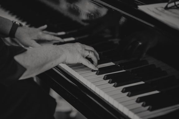 Hände spielen auf einem Klavier mit schwarzen und weißen Tasten.