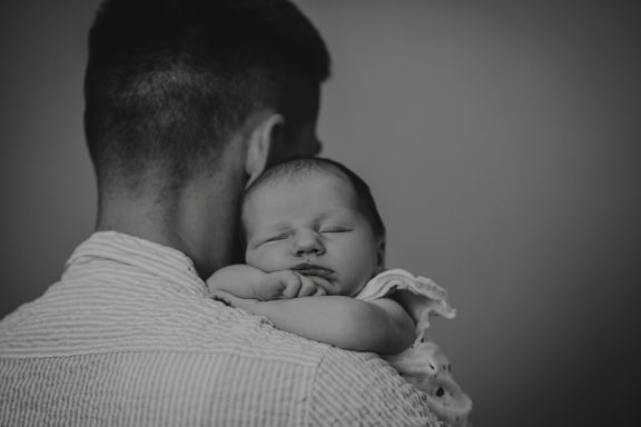 Ein Erwachsener hält ein schlafendes Baby in den Armen.