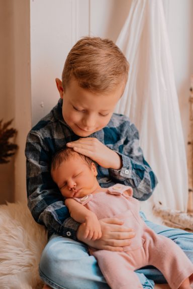Ein Kind hält liebevoll ein schlafendes Baby auf seinem Schoß.