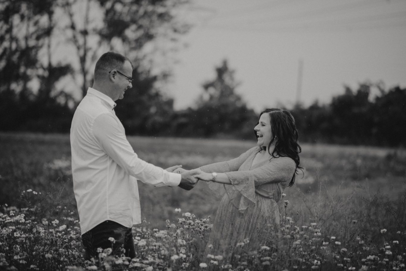 Paar in einem Feld, das sich an den Händen hält und lächelt.